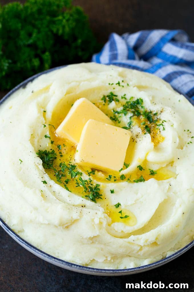 Garlic Mashed Potatoes Recipe #garlic #potatoes #mashedpotatoes #sidedish #dinner #thanksgiving #dinneratthezoo Garlic mashed potatoes topped with pats of butter and fresh parsley, presented beautifully on a serving dish.