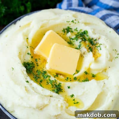 Garlic mashed potatoes topped with pats of butter and parsley, ready to be served as a delightful side dish.