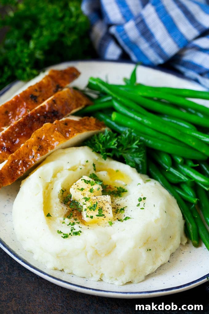 Garlic Mashed Potatoes Recipe #garlic #potatoes #mashedpotatoes #sidedish #dinner #thanksgiving #dinneratthezoo A beautifully plated meal featuring a generous serving of garlic mashed potatoes, vibrant green beans, and tender sliced turkey, perfect for a holiday dinner.
