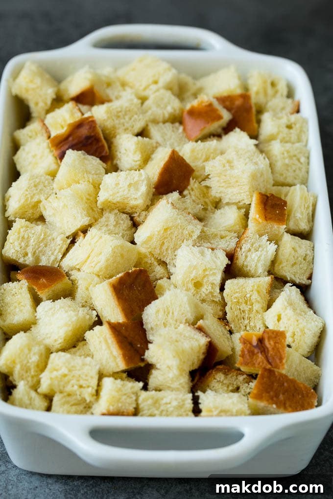 Close-up shot of challah bread cubes arranged neatly in a baking dish, ready for the custard.