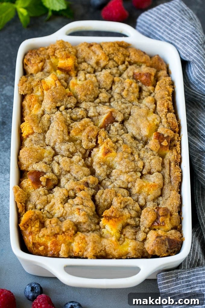 A baking dish filled with French toast casserole, elegantly topped with a generous layer of glistening brown sugar streusel.
