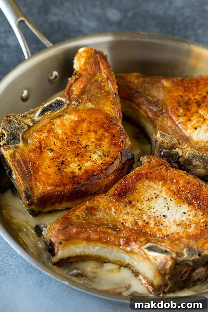 Pork chops returned to the pan, covered in creamy mushroom and onion gravy.