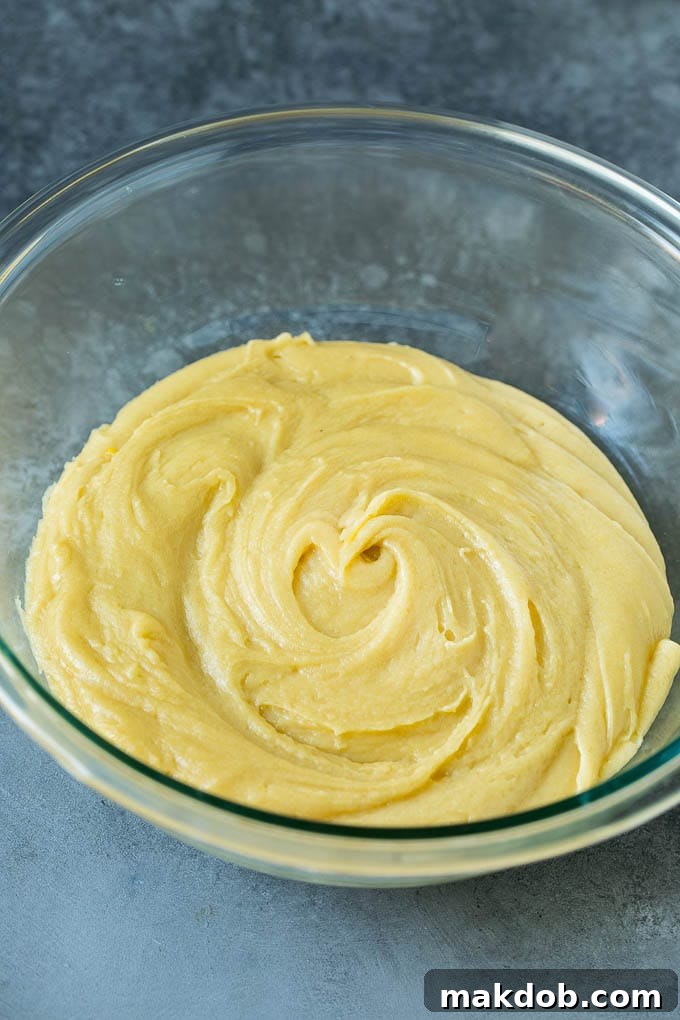 Smooth vanilla-flavored cookie dough in a large glass mixing bowl, ready for baking.