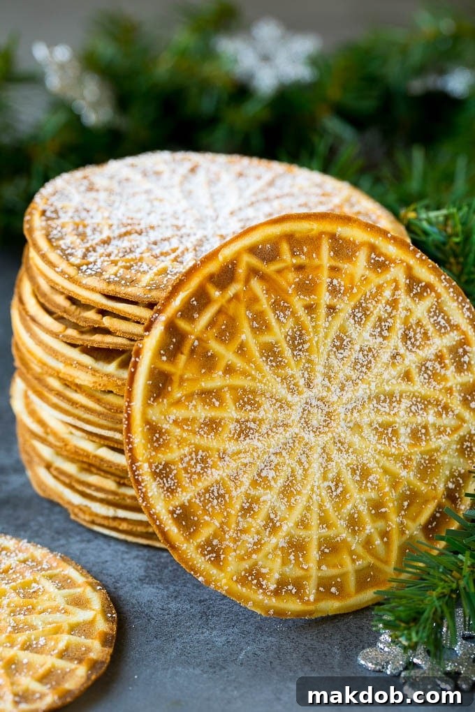 A beautifully arranged stack of traditional pizzelle cookies, generously dusted with powdered sugar.