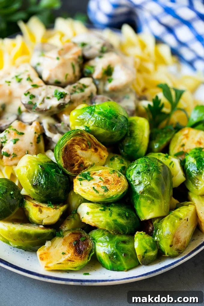 Sauteed Brussels Sprouts Recipe | Brussels Sprouts Side Dish #brusselssprouts #sprouts #veggies #sidedish #garlic #vegetarian #dinner #dinneratthezoo Sautéed brussels sprouts served beautifully alongside a main course of chicken and noodles, showcasing a complete meal.