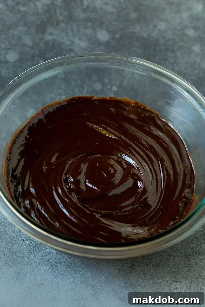 Smooth, glossy semi-sweet chocolate ganache resting in a glass mixing bowl.