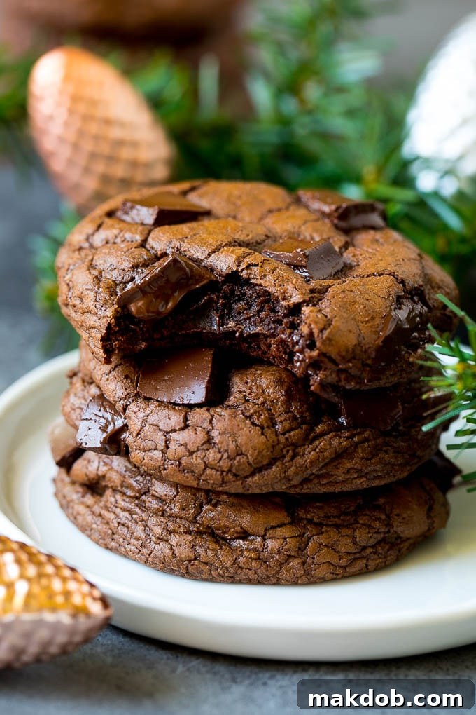 A stack of rich brownie cookies with a bite taken out of one, revealing its soft, fudgy interior.