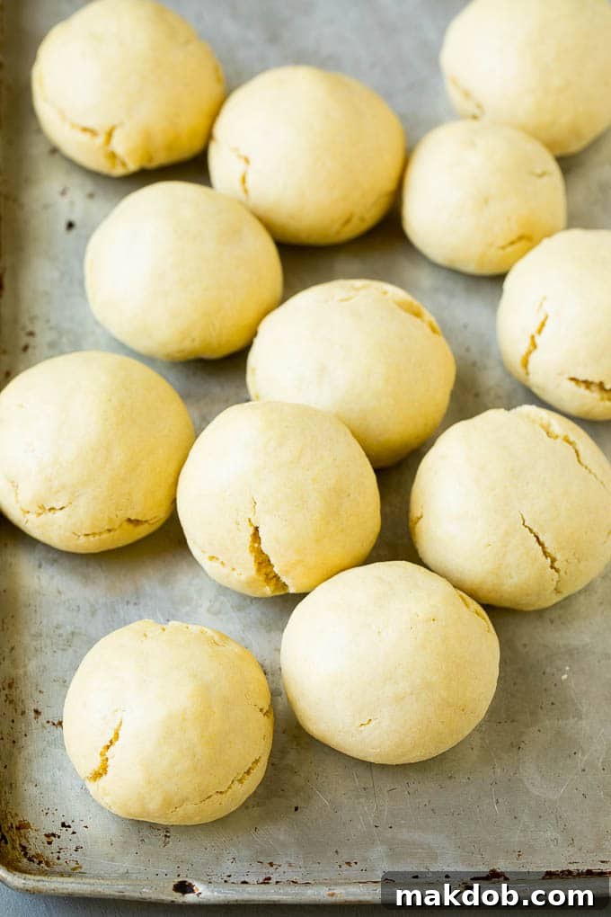 Baked almond cookies cooling on a baking sheet, ready for frosting.
