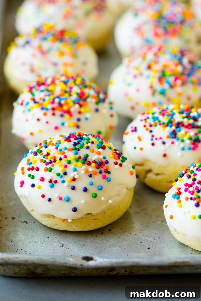 Italian cookies covered in frosting and rainbow sprinkles, arranged beautifully on a plate.