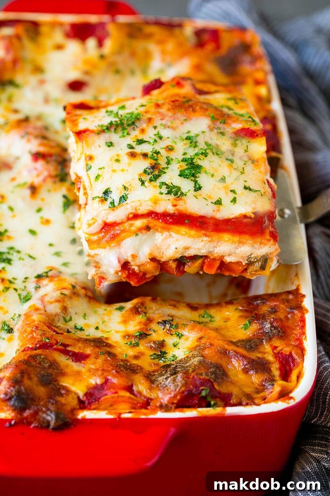 Vegetable Lasagna Recipe | Vegetarian Lasagna #lasagna #vegetarian #veggies #cheese #pasta #dinner #dinneratthezoo A spatula scooping up a generous portion of vegetable lasagna from a baking dish.