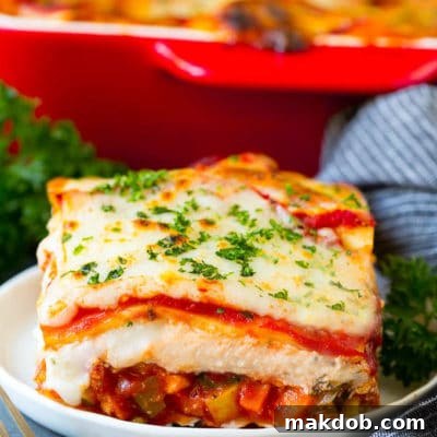 Vibrant Veggie Lasagna 2 A slice of vegetable lasagna topped with melted cheese and parsley.