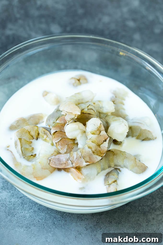 Raw shrimp in a bowl of buttermilk.