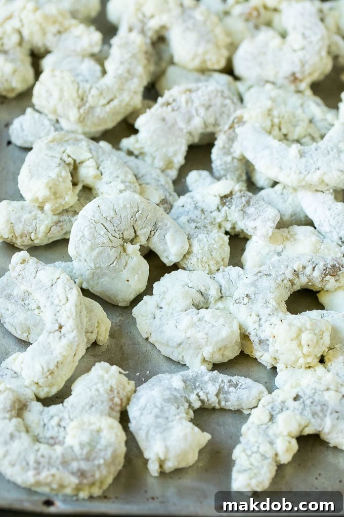 Shrimp coated in cornstarch on a sheet pan.