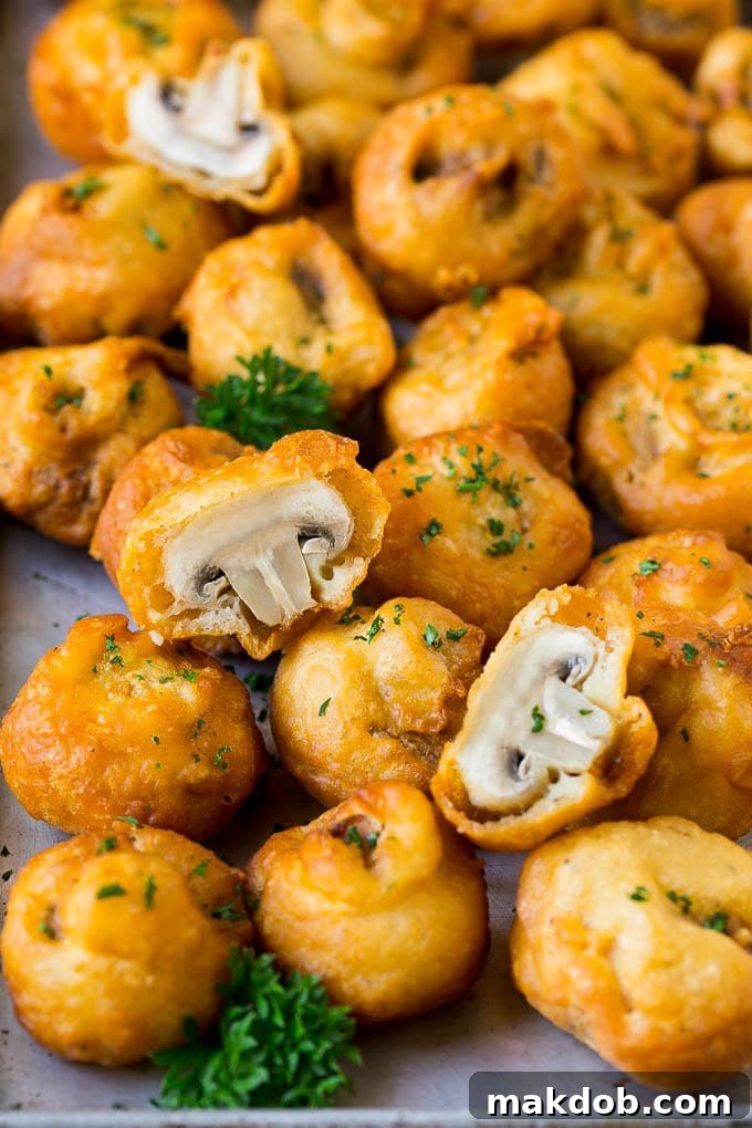 Fried Mushrooms Recipe #mushrooms #appetizer #snack #dinneratthezoo A sheet pan of golden-brown fried mushrooms garnished with fresh parsley, ready to be served as an appetizer.