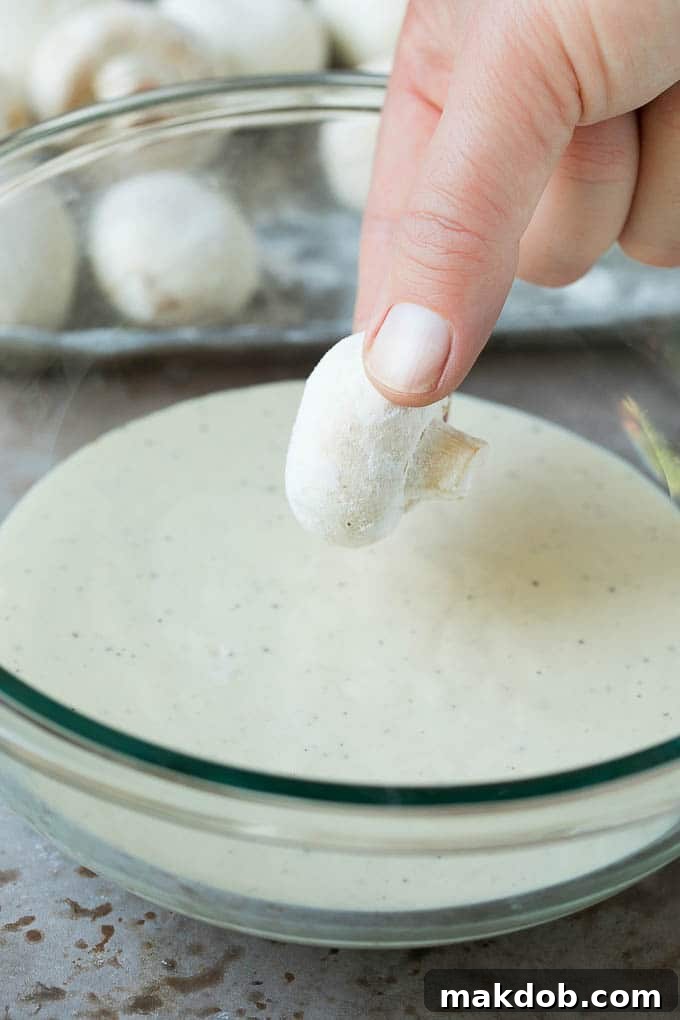 Fried Mushrooms Recipe #mushrooms #appetizer #snack #dinneratthezoo A mushroom being dipped into beer batter.