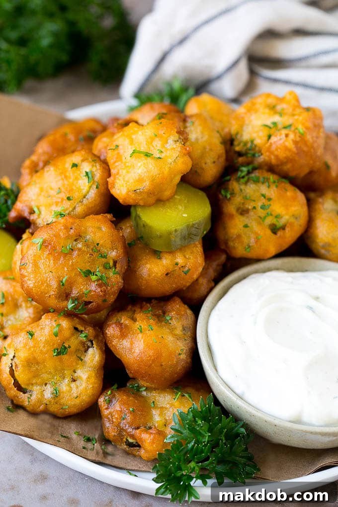 A plate of crispy golden-brown fried pickles, perfectly deep-fried and served with a creamy ranch dip for dipping. Ideal for parties or game day snacks.