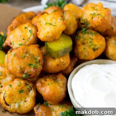 A plate of crispy golden-brown fried pickles, perfectly deep-fried and served with a creamy ranch dip for dipping.