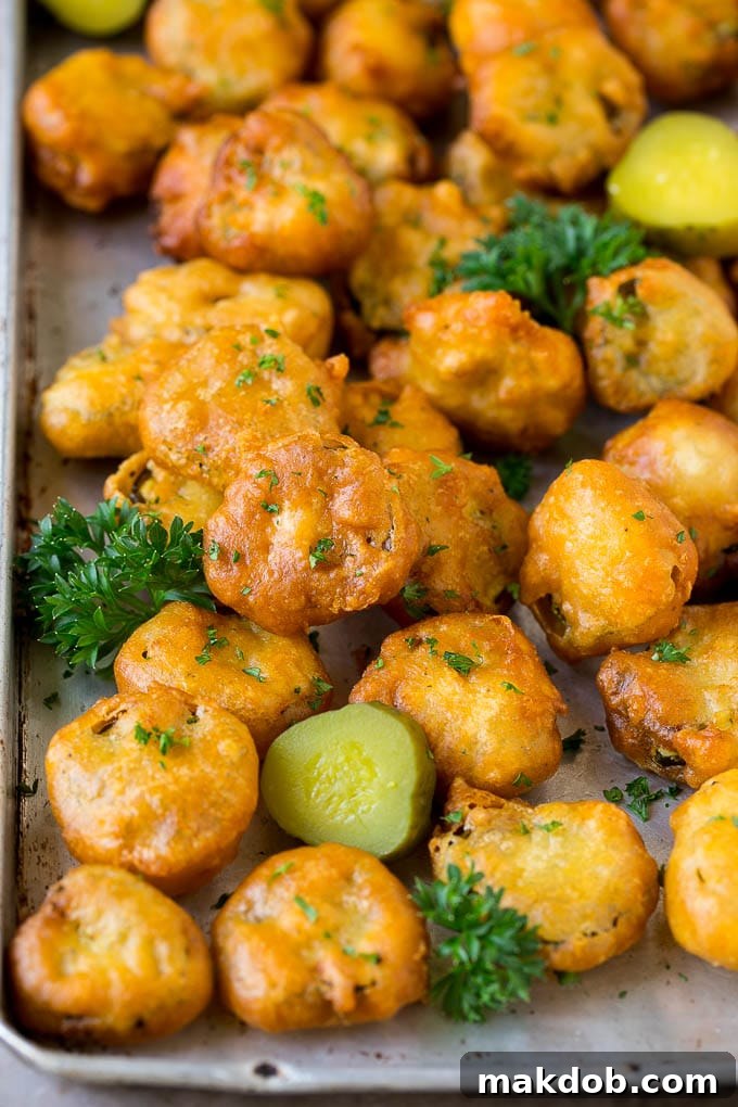 A generous serving of crispy golden fried pickles, beautifully garnished with fresh parsley and ready to be devoured, displayed on a sheet pan.