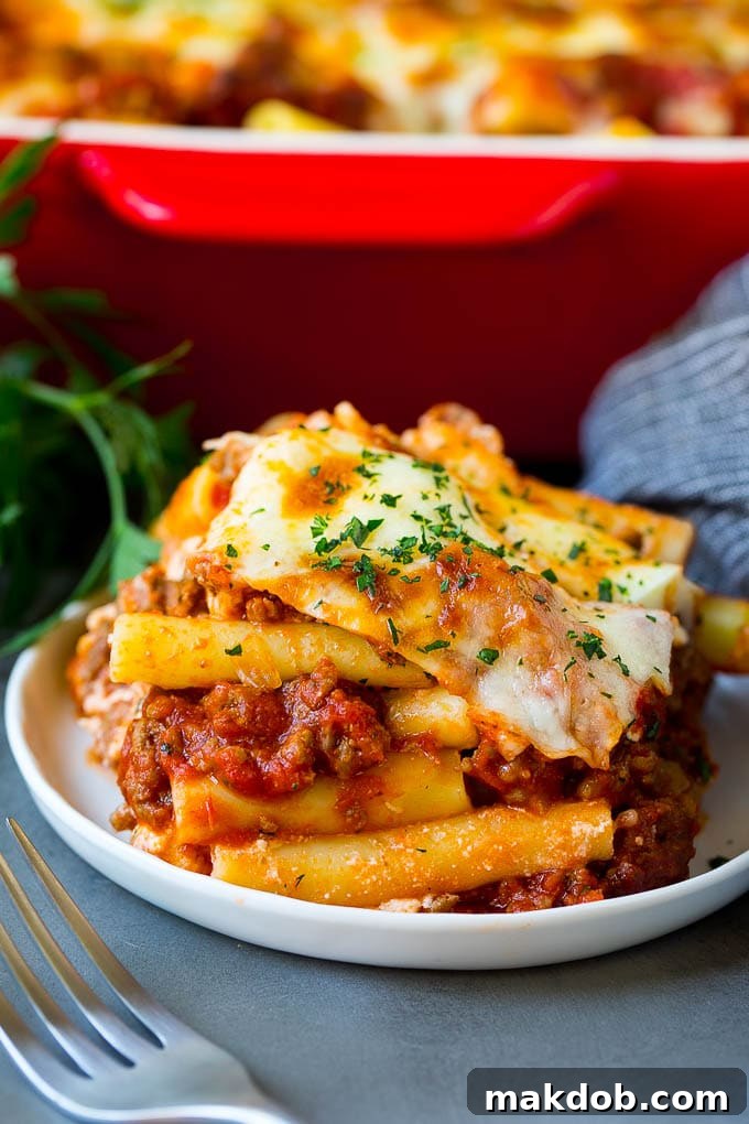 A serving of baked ziti with meat sauce and ricotta cheese, garnished with fresh herbs.