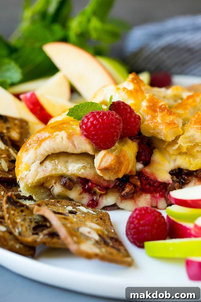 A cross section of baked brie filled with raspberries and pecans.