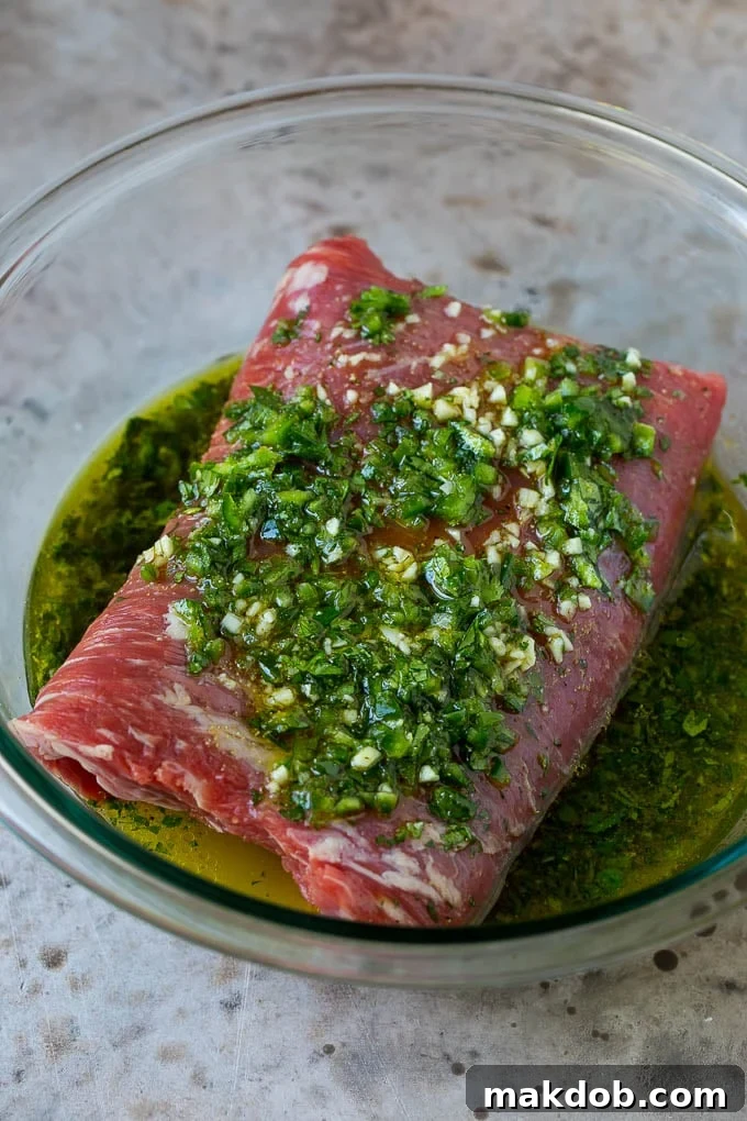 Flank steak in a cilantro and citrus marinade, ready for grilling, showcasing the fresh ingredients for Carne Asada.