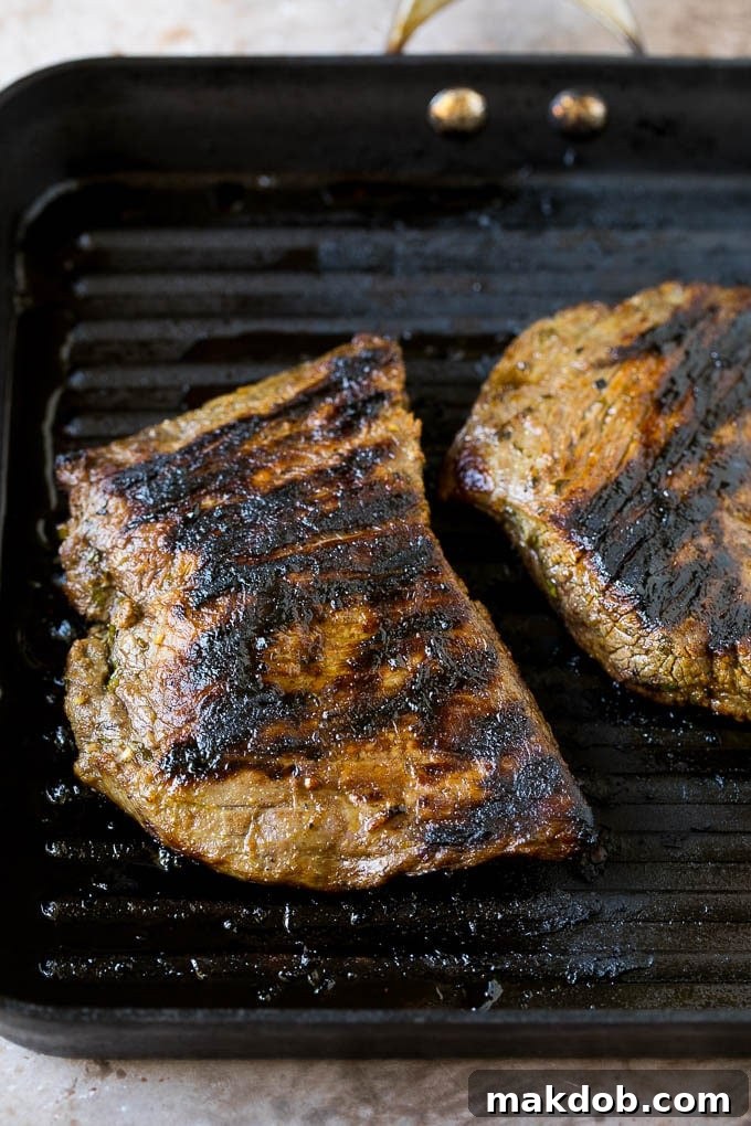 Grilled carne asada steak in a pan, beautifully seared and ready to be sliced for the fries.