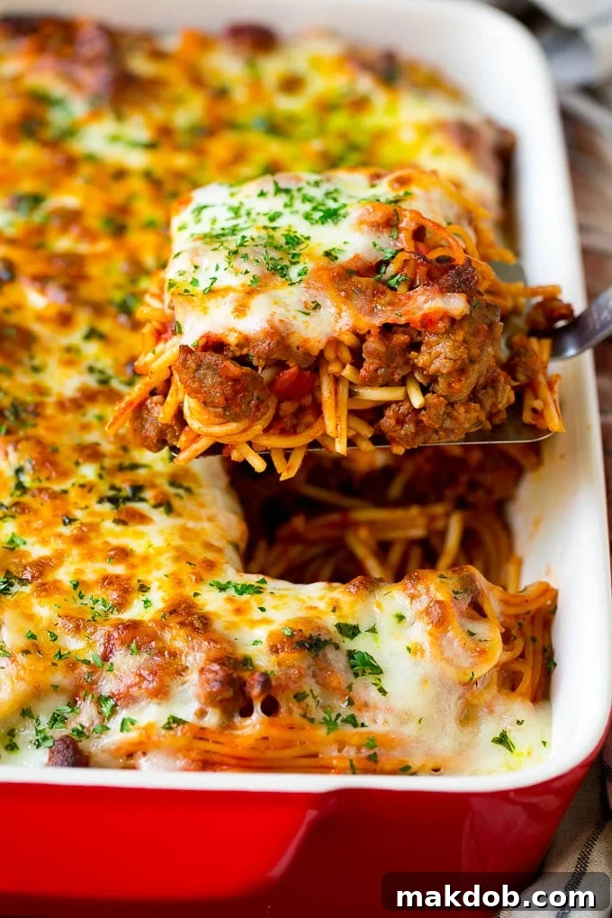 Delicious Baked Spaghetti Recipe | Easy Cheesy Pasta Casserole A spatula holding up a serving of baked spaghetti, showcasing melted cheese and rich meat sauce.