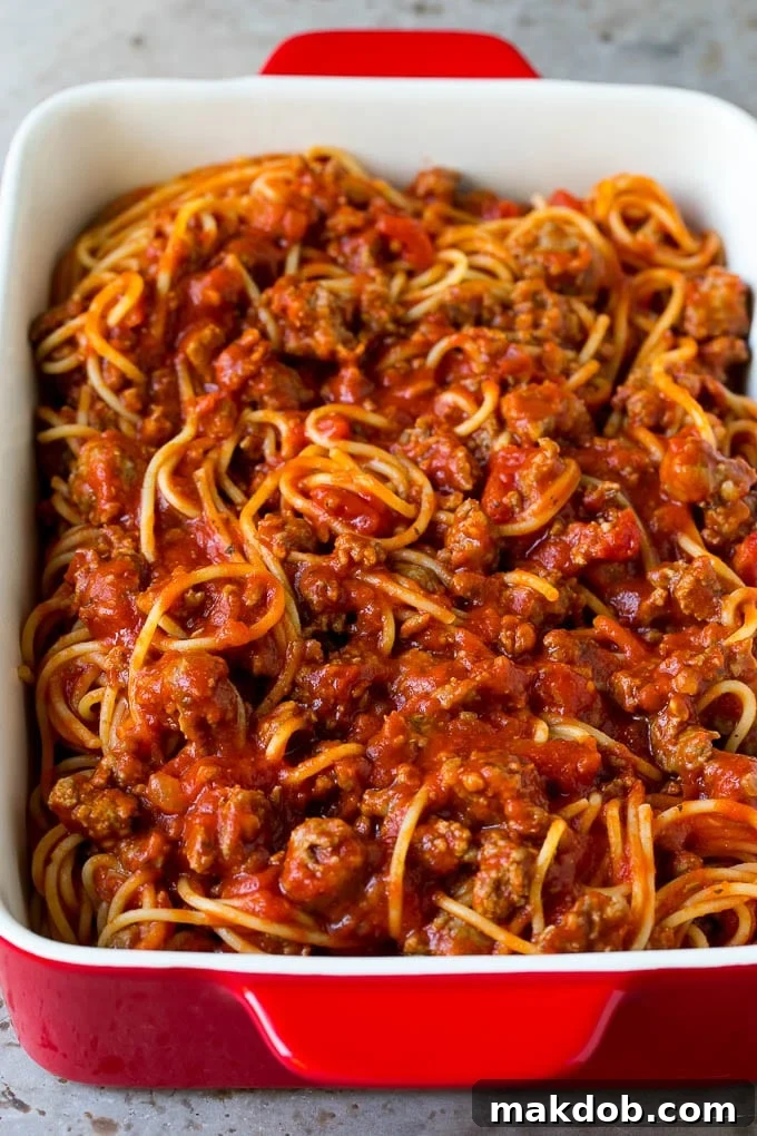 Spaghetti with Meat Sauce in Baking Dish Cooked spaghetti tossed with a rich meat sauce, ready to be topped with cheese and baked.