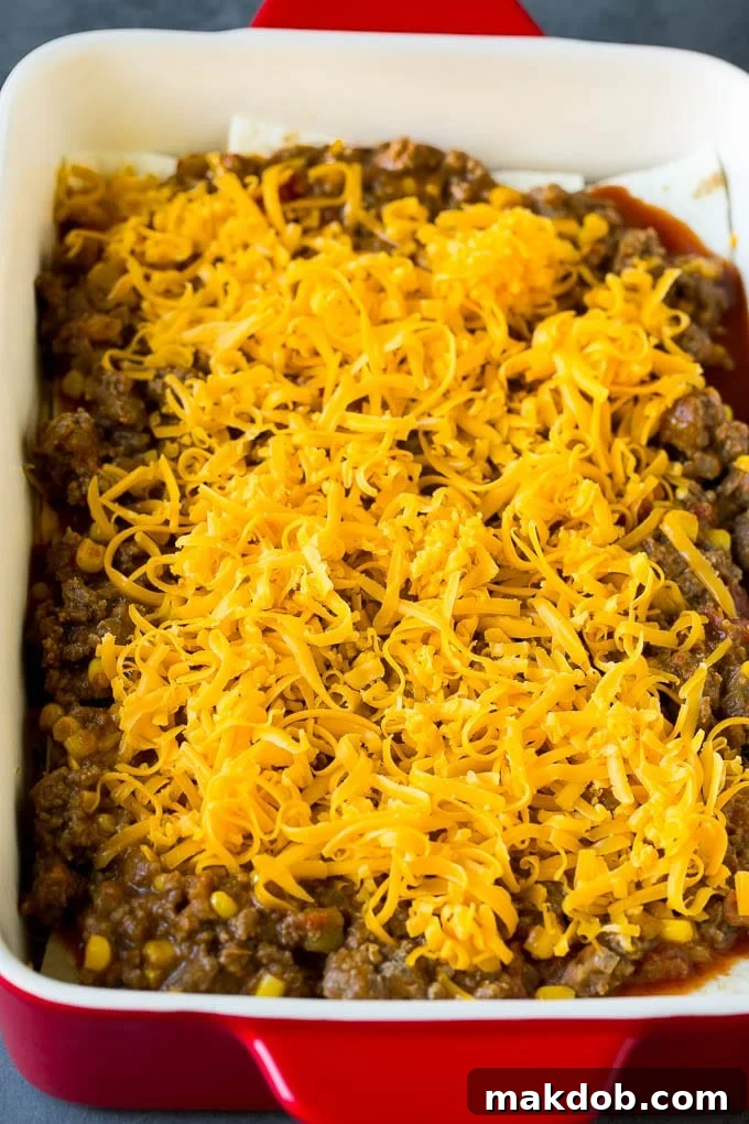 Mexican Lasagna Recipe | Mexican Casserole #mexican #lasagna #groundbeef #beans #dinner #cheese #dinneratthezoo Layers of tortillas, ground beef and shredded cheese in a baking dish.