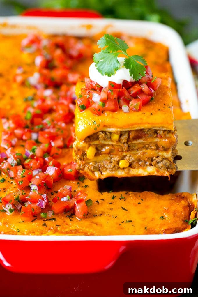 Mexican Lasagna Recipe | Mexican Casserole #mexican #lasagna #groundbeef #beans #dinner #cheese #dinneratthezoo A spatula serving up a portion of Mexican lasagna.