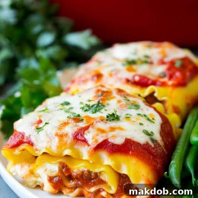Lasagna roll ups with meat sauce, served with a side of green beans.
