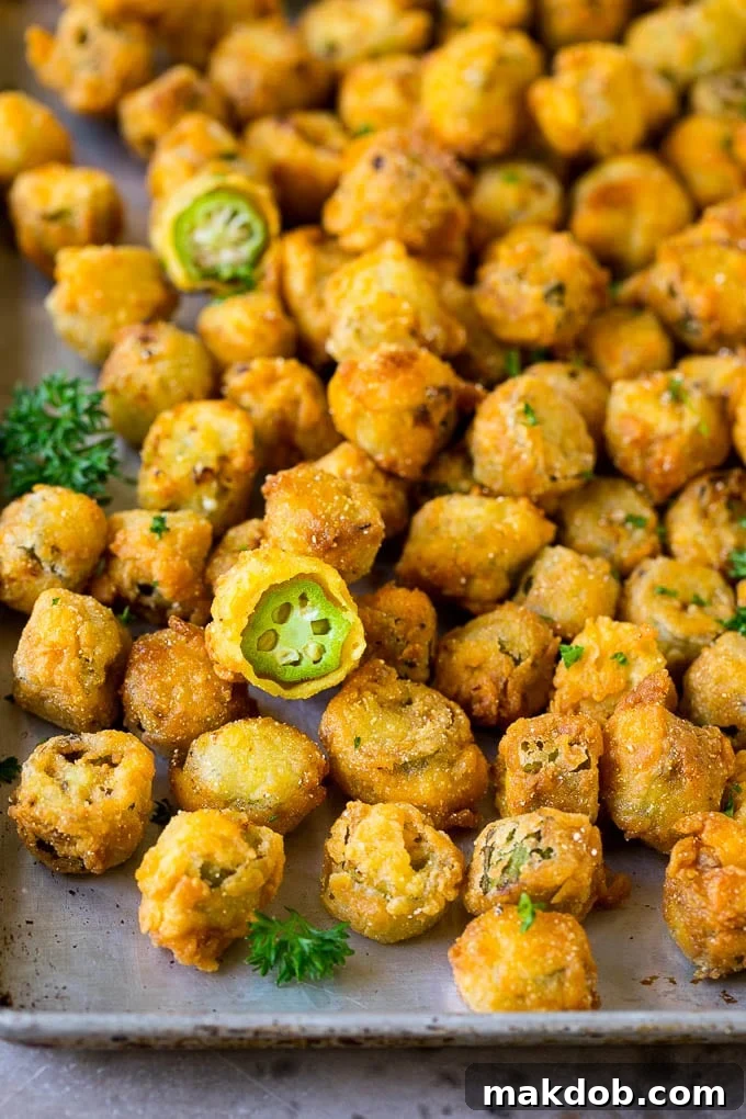 Fried okra on a sheet pan, garnished with chopped parsley.