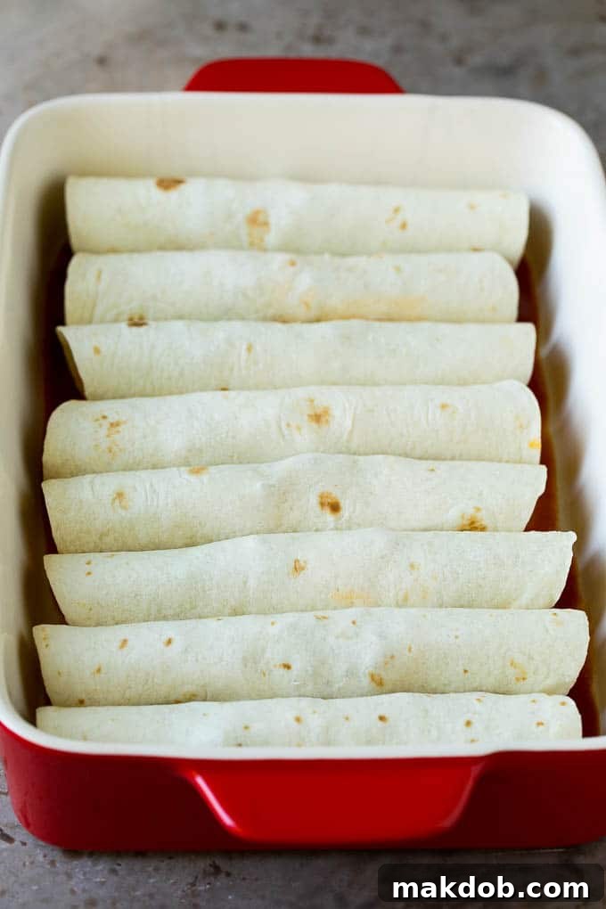 Flour tortillas wrapped around ground beef in a baking dish.