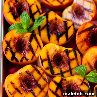 Grilled peaches garnished with raspberries and fresh mint.