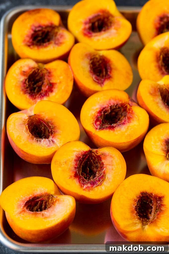 Peaches cut in half on a sheet pan.
