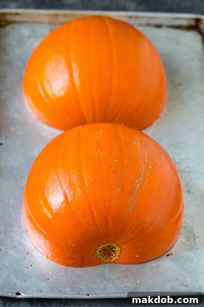Pre-Roast Sugar Pie Pumpkin Halves Two halves of a sugar pie pumpkin on a baking sheet, ready for roasting, highlighting the rich orange flesh and preparing for a flavorful pumpkin soup.