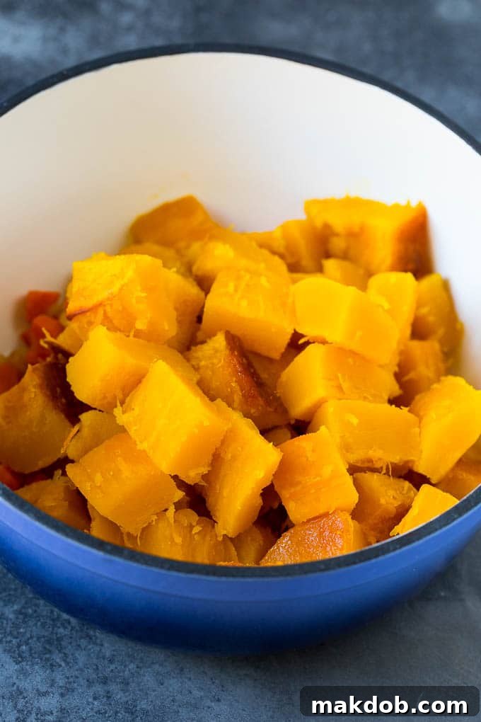 Roasted Pumpkin Cubes in Soup Pot Cubed roasted squash in a large pot with other ingredients, ready to be blended into a creamy soup.