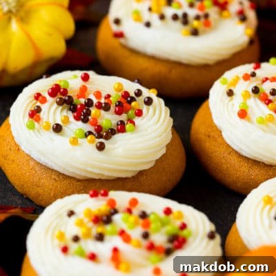 Decadent Pumpkin Spice Cookies with Creamy Frosting 2 Soft pumpkin cookies topped with cream cheese frosting and fall sprinkles.