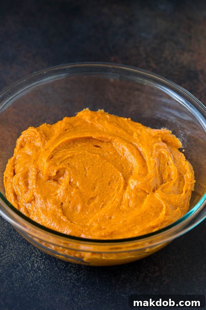 A close-up of the delicious pumpkin cookie dough being mixed in a bowl, ready for chilling. Mixing cookie dough in a bowl, showcasing the rich orange color of pumpkin.