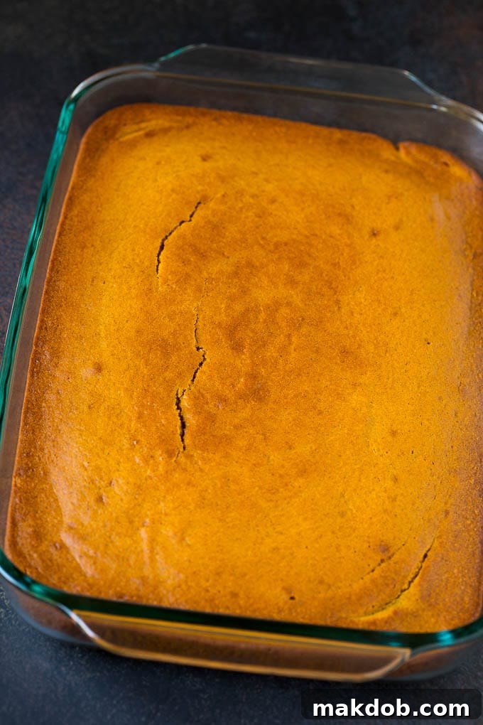 A baked pumpkin cake base in a glass baking dish, ready for the cream cheese frosting.