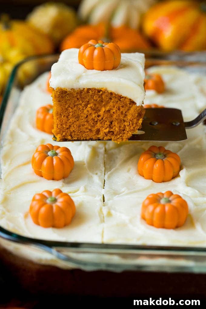 A serving spatula lifting a perfect slice of pumpkin cake, showcasing its moist texture and thick frosting.