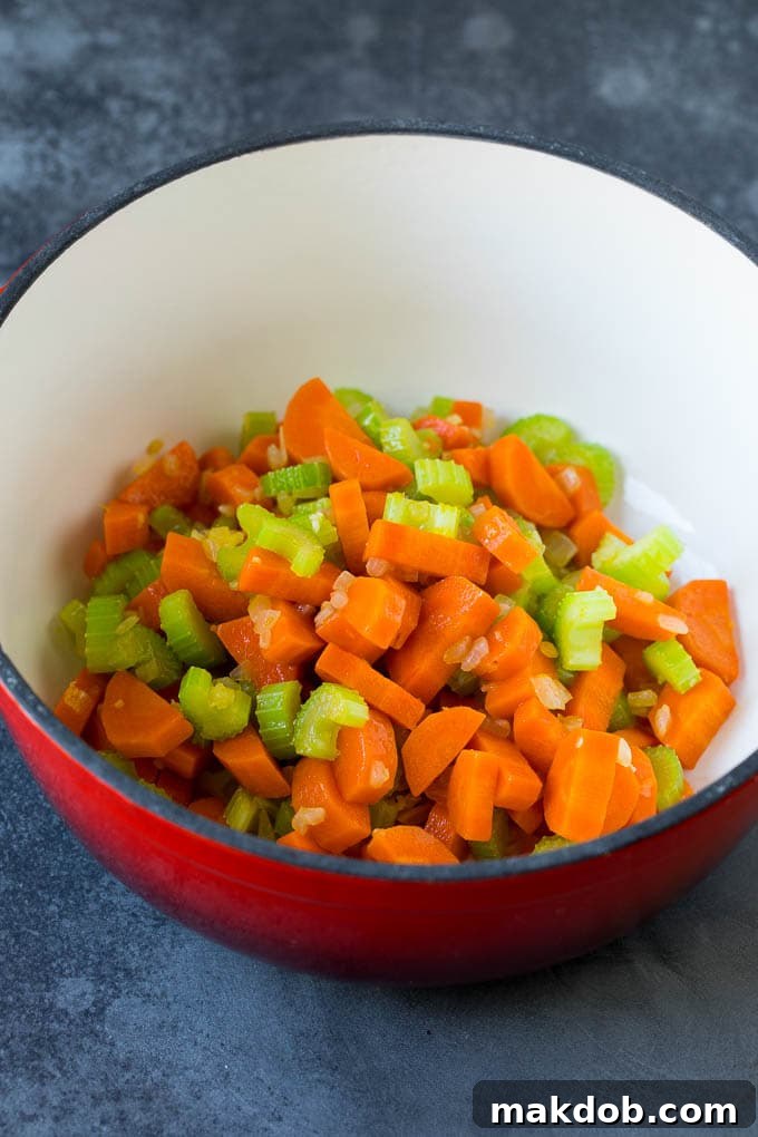 Finely diced carrots, onions, and celery glistening as they cook in olive oil in a large soup pot, releasing their aromatic scents.