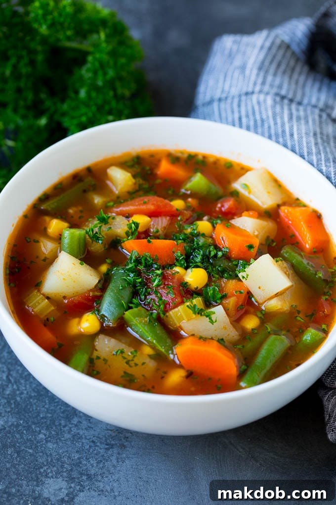 A steaming bowl of homemade vegetable soup, beautifully garnished with fresh green parsley, clearly showcasing the vibrant green beans, tender potatoes, bright orange carrots, and sweet yellow corn.