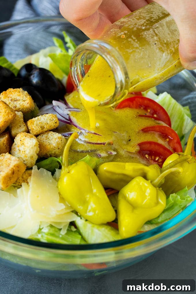 Dressing being poured over a bowl of salad.