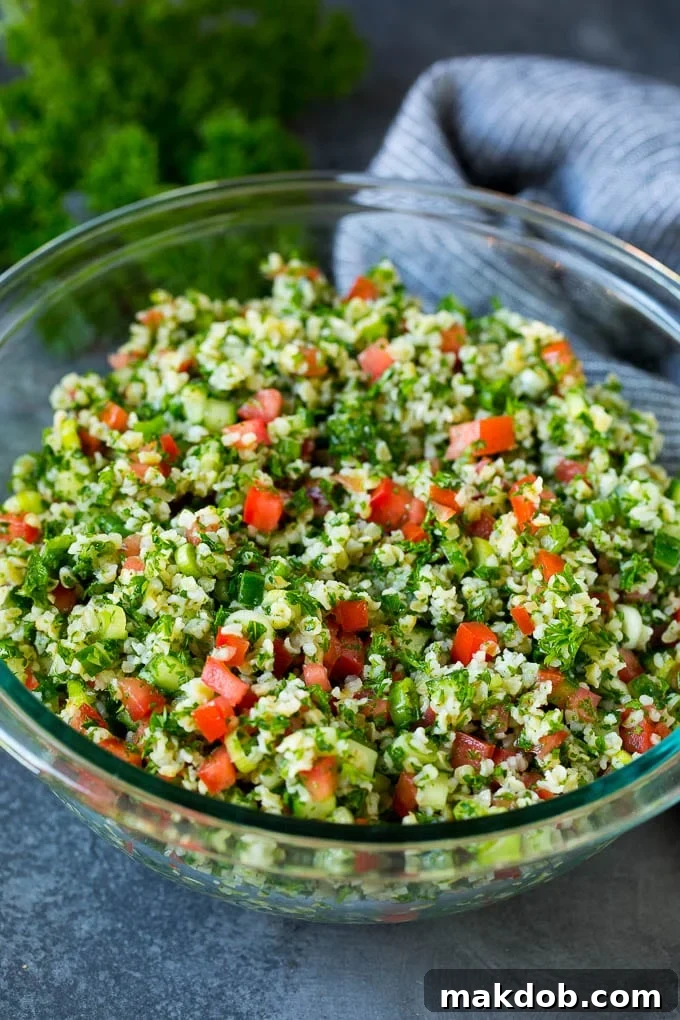 A beautifully presented serving bowl filled with fresh, vibrant tabbouleh salad, garnished with a sprig of mint, ready for sharing.