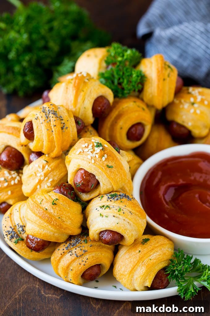 A plate of pigs in a blanket served with ketchup.