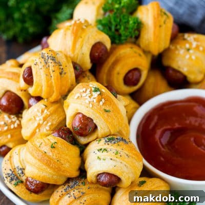 A plate of pigs in a blanket served with ketchup.