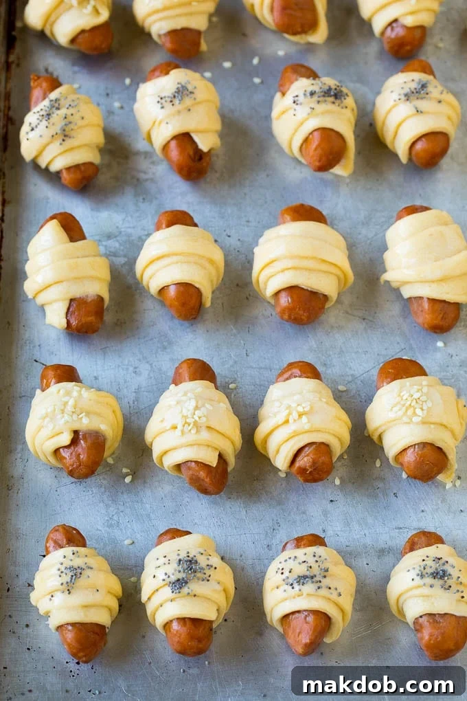 Mini hot dogs wrapped in crescent dough and topped with seeds.