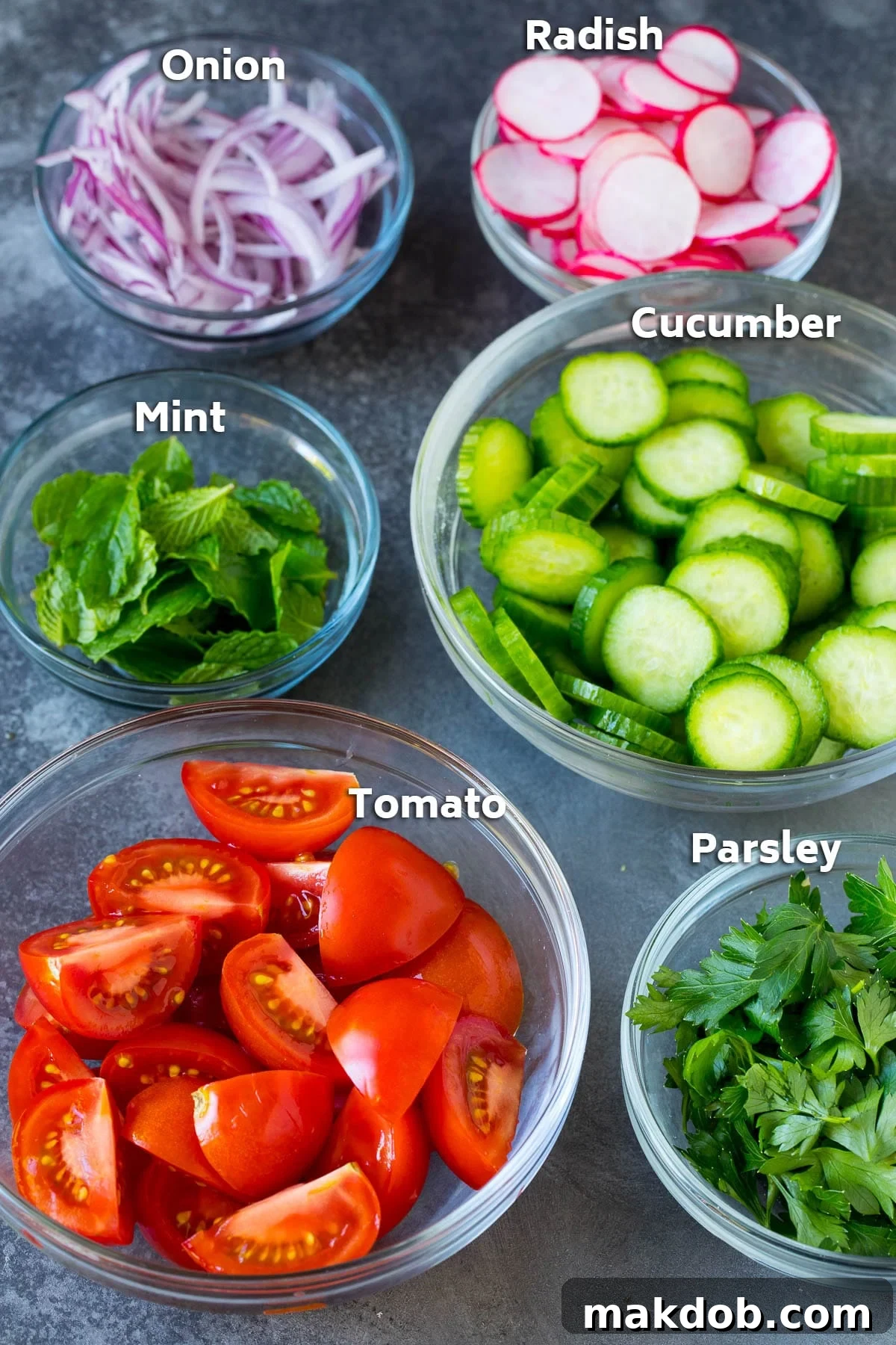 Glass bowls neatly arranged with an assortment of fresh vegetables and aromatic herbs, ready for a Fattoush salad.
