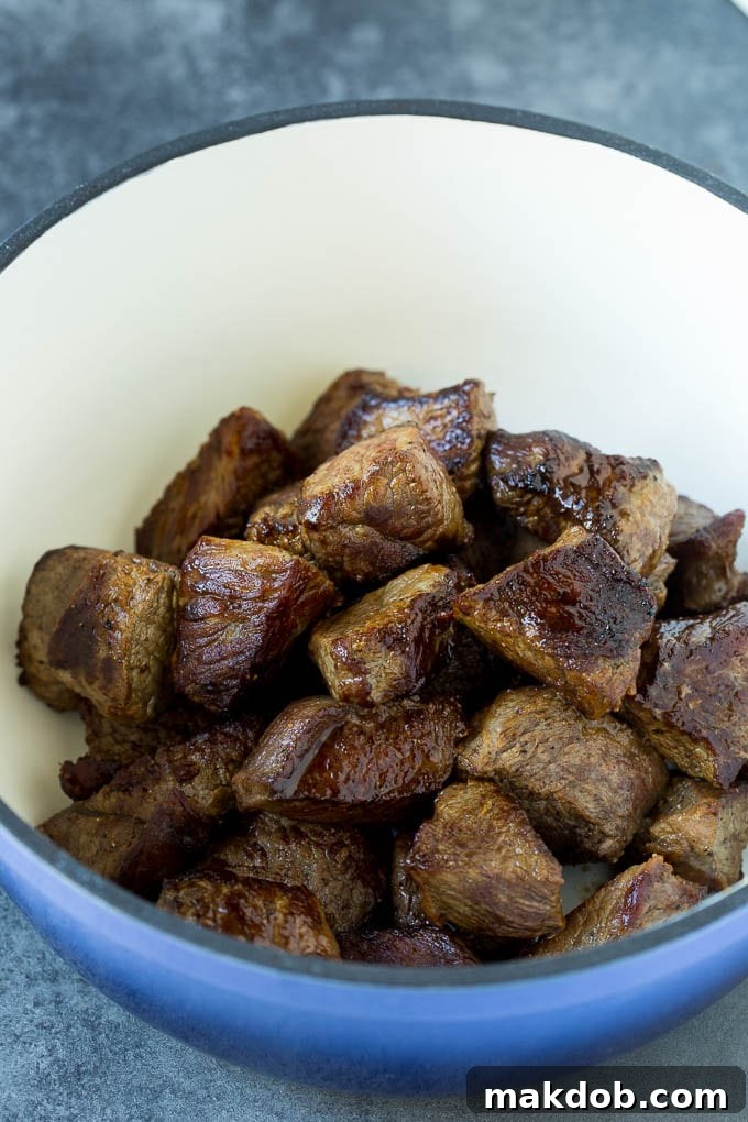 Searing Beef for Rich Irish Stew Flavor Browned beef cubes sizzling in a large Dutch oven, a crucial step for building flavor in Irish stew.